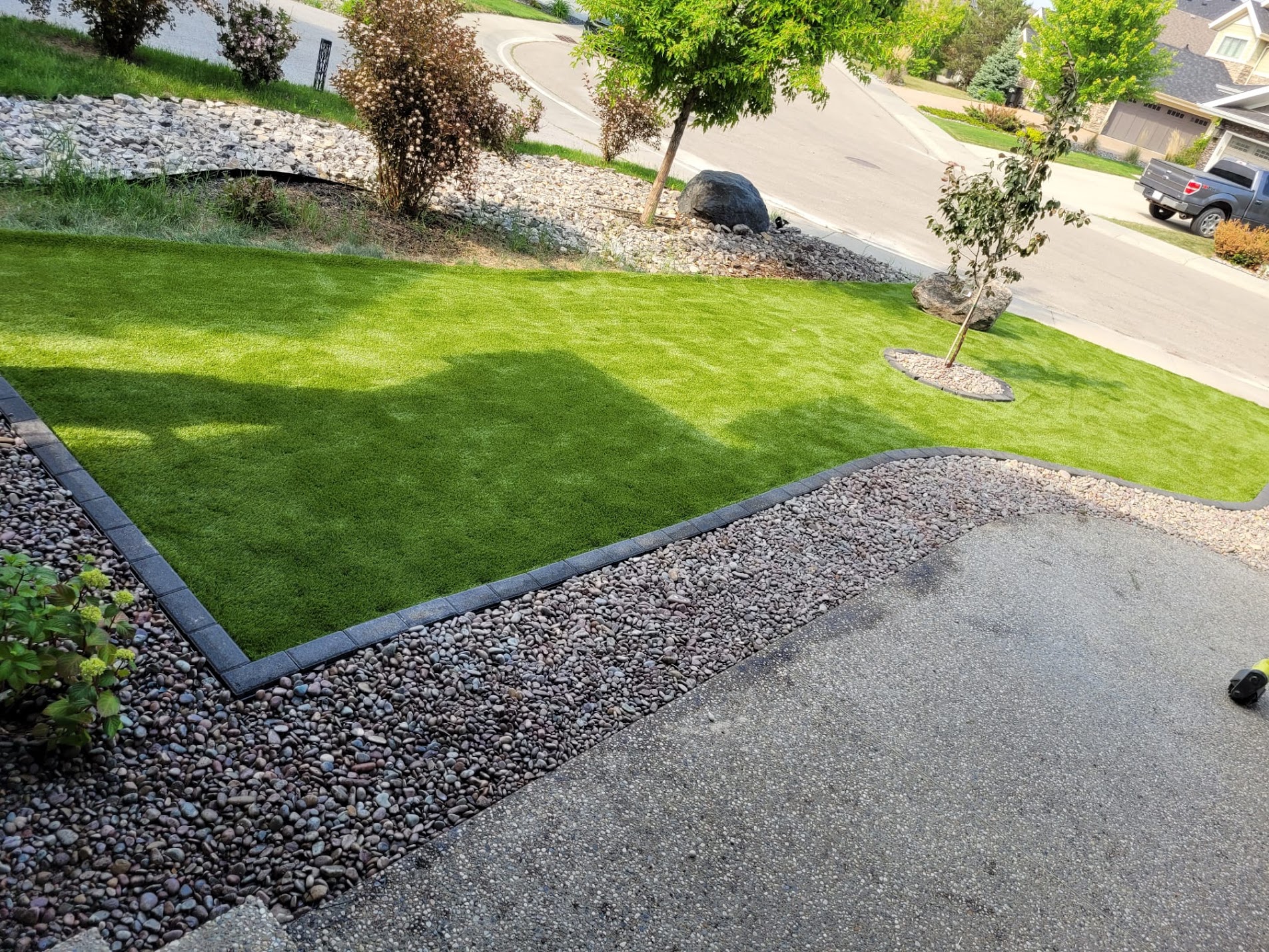Front yard artificial turf with paver edging and decorative rock bed